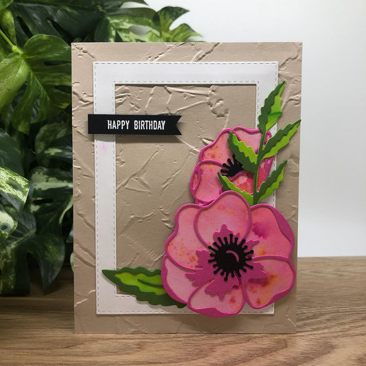A handmade birthday card with a beige background, featuring a colorful floral design with the words 'Happy Birthday' written on it.